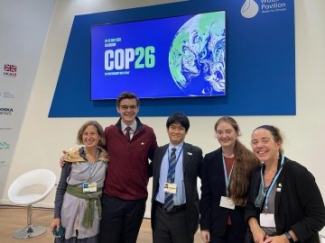 Elise Pierson and fellow delegates, wearing business professional attire and lanyards, attend the United Nations climate awareness conference. 