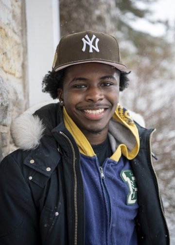 Marteas Johnson, standing outside a brick building on a snowy day, wearing a New York Yankees ball cap and several warm layers of clothing.