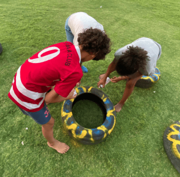 Three children paint tires for a sustainable portion of a new playground in Egypt. 