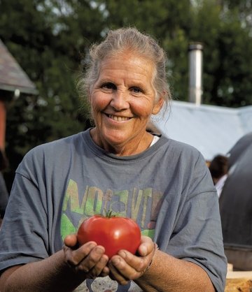 A photo of Enid Wonnacott smiling with a tomato in her hands.