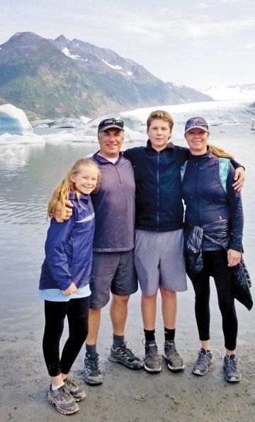 The Frielander family posing together and smiling in front of a glacier and lake. 