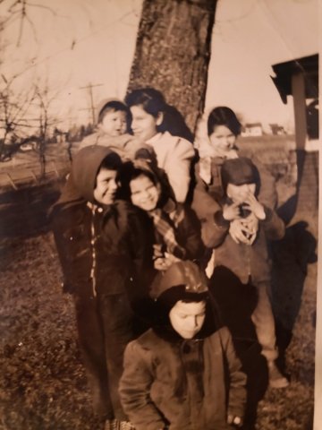 A sepia toned image of a Mohawk family in front of a tree