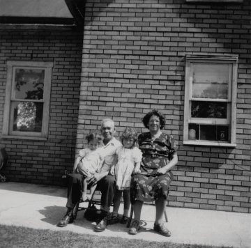 Black and white photo of a family in front of a brick building