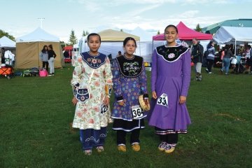 Three women dressed in traditional Mohawk garments