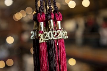 Scarlet and Brown graduation cap tassels with Class of twenty-twenty-two charms dangling from them.