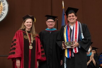 Wearing graduation regalia, President Morris and Mike Ranger stand with Eduardo Puerta, this year's Jeffery H Boyd Class of 1978 Prize winner. 
