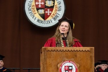 President Morris, wearing Commencement regalia and standing at a podium, addresses the Class of 2022 during this year's Commencement ceremony. 