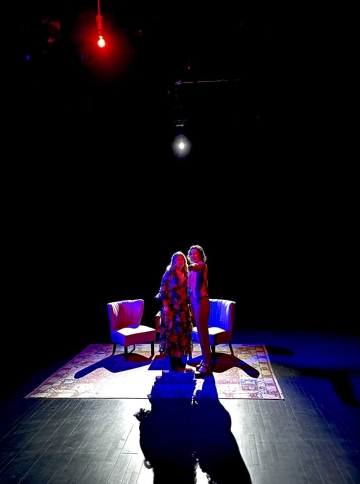 Image of two women dimly illuminated by a light bulb above