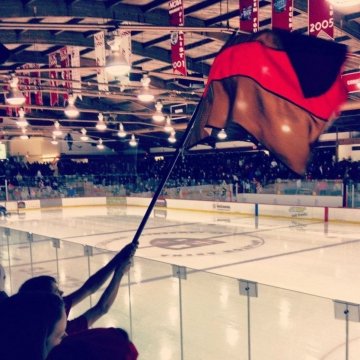 Evan waiving a Saints scarlet and brown flag at Appleton Arena