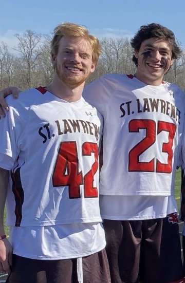 Chris Jordan and William Helm, wearing white lacrosse jerseys with scarlet numbers.