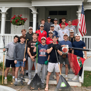 Group photo of the Saint Lawrence Mens Baseball team standing with their rakes after helping clean up leaves in the community.