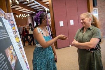 Sarath Novas discusses her research presentation with Professor Sara Ashpole.