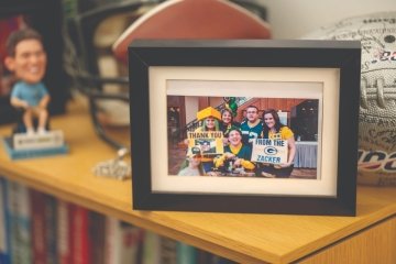 A group of Green Bay Packers football fans wear fangear and hold up large signs that say, "Thank you from the Zacker."