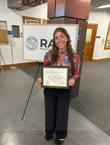 female student holding award and smiling