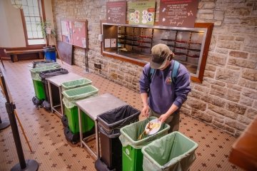 A student scrapes their food plate into compositing bins in Dana Dining Hall.