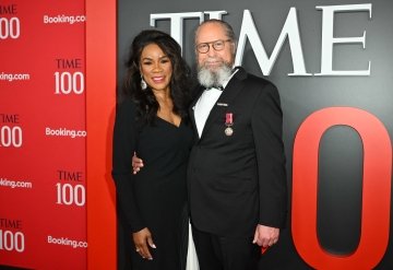 Robert Montgomery, wearing a tuxedo, stands with his wife in front of a TIME 100 backdrop.