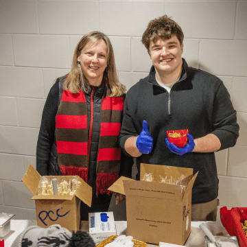 Connor Simons ’28 and President Kate Morris helping the Laurentian Engagement team serve scoops of Pub Cookie Crunch to students and community members at the Route 11 Rivalry game