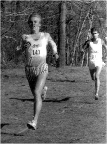 A tall slim male athlete sprinting toward the finish of a distance race.