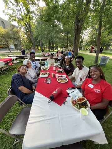 College students sitting at outdoor dining table with food