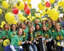 A photo of Kappa Delta Sigma alum all wearing the same shirts posing as dozens of balloons float above them.