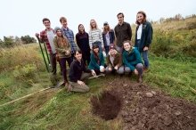 A photo of Ceramics 1 students posing in a field behind a large hole they dug.