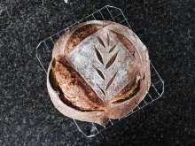 A close up photo of a freshly baked loaf of bread with a leaf design cut into the top.