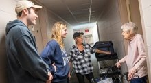Saint Lawrence students and a mentor chat with a resident at a nursing home facility.