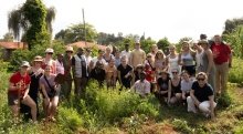A group of smiling people gather together outside on a sunny day in Kenya.