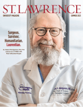 Close-up of Dr. Robert Montgomery wearing a white NYU Langone Health lab coat, smiling warmly on the cover of Saint Lawrence University Magazine, Summer 2025 issue. Text beside him reads: “Surgeon. Survivor. Humanitarian. Laurentian.”