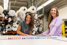 Carey Scully Strobeck and her creative partner laugh while looking at fabric samples.